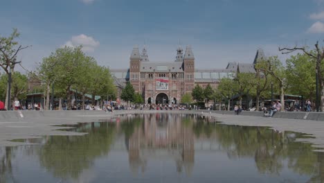Great-long-shot-of-the-Rijksmuseum-reflected-in-a-puddle-located-at-Museumplein-6,-Amsterdam,-Netherlands-on-a-sunny-day