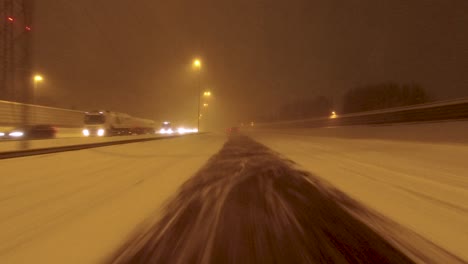 POV-shot-driving-past-a-very-busy-highway-in-heavy-snow-in-Helsinki,-Finland