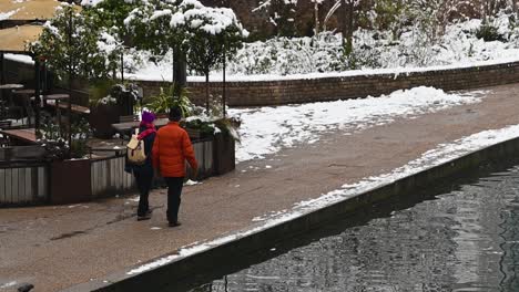 Couple-walking-along-Regents-Canal-on-a-snowy-day,-London,-United-Kingdom