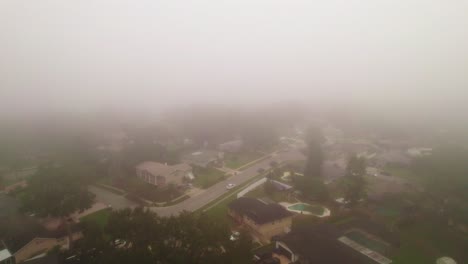Aerial-reverse-flyover-through-foggy-and-misty-neighborhood-in-city-of-Ocoee,-Florida-with-no-vehicles-driving