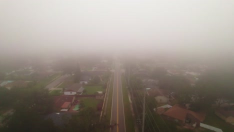 Aerial-flyover-of-foggy-and-misty-road-through-city-of-Ocoee,-Florida-with-no-vehicle-driving