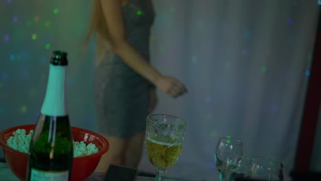 Beautiful-blonde-caucasian-white-girl-women-in-front-of-led-light-wall-in-a-dark-night-club-scene-neck-down-shot-as-she-dances-twists-and-lets-loose-with-champagne-wine-and-popcorn-at-night-club