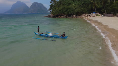 Drone-view-of-men-sailing-a-boat-on-tropical-beach
