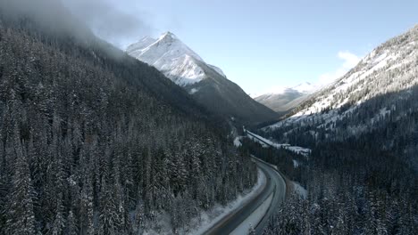 Trans-Canada-Highway-1-Winter-Journey:-Vehicles-Travel-Across-Scenic-Landscape-with-Majestic-Mountains-in-Revelstoke,-British-Columbia