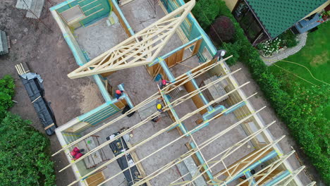 Aerial-drone-top-shot-of-workers-building-a-roof-for-a-home-made-from-wood