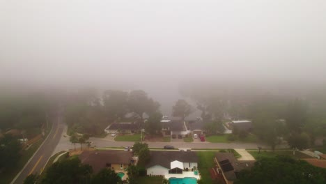 Aerial-flyover-through-foggy-and-misty-neighborhood-in-city-of-Ocoee,-Florida-with-no-vehicles-driving