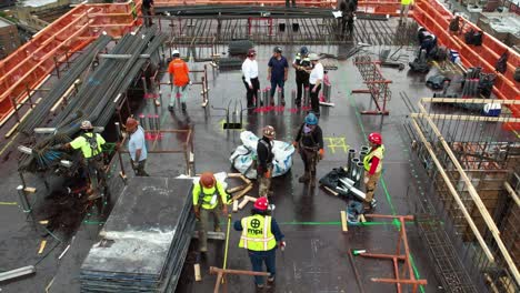 Workers-having-a-meeting-on-top-of-a-high-rise-constrution-site,-in-Queens,-NY---aerial-view