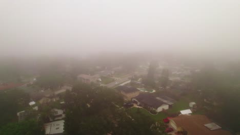 Aerial-flyover-through-foggy-and-misty-neighborhood-in-city-of-Ocoee,-Florida-with-no-vehicles-driving-and-nobody-outside
