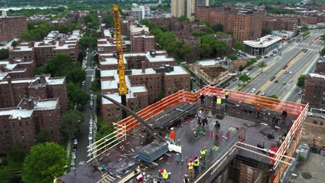 Aerial-view-around-a-crane-lifting-rebar-to-workers-on-top-of-a-building-in-New-York