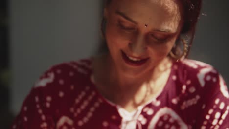 Porträt-Einer-Indischen-Frau-Mit-Einem-Schönen-Lächeln,-Die-Nach-Unten-Schaut-Und-Ein-Rotes-Sommerkleid-Trägt,-An-Einem-Sonnigen-Tag-In-Fontainhas,-Indien