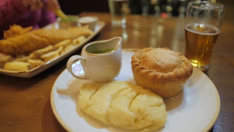 Pie-And-Mash-Served-With-Liquor-With-A-Plate-Of-Fish-And-Chips-In-The-Background