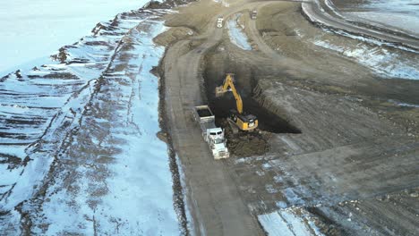 An-excavator-dumps-dirt-into-a-waiting-heavy-haul-truck-on-a-new-build-project-West-of-Calgary,-Alberta-Canada