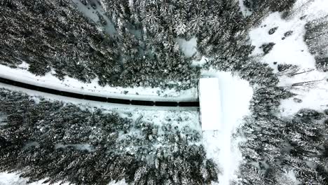 Breathtaking-Overhead-Shot-of-Cargo-Tanker-Train-Entering-Tunnel-Through-Railway-running-in-Snowy-Forests-Mountainous-terrain