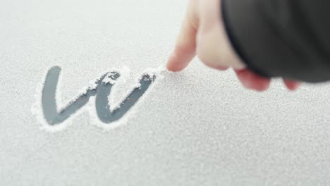 POV-person-writing-word-winter-on-car-window-in-snow-with-finger