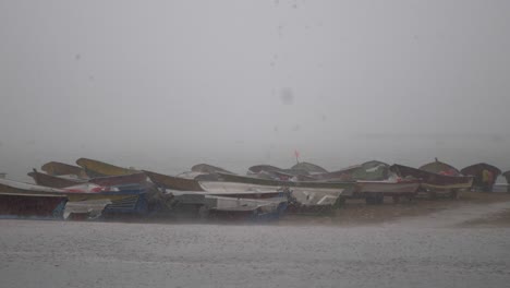 Row-Of-Empty-Small-Fishing-Boats-Resting-On-Gwadar-Beach-During-Heavy-Downpour-Rain