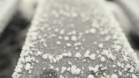 Tiny-snowflakes-frozen-on-metal-object,-moving-backward-view