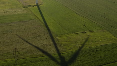 Rotating-wind-turbine-blades-casting-shadow-on-fields-in-Gori,-Georgia