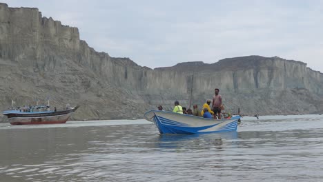 Junger-Pakistanischer-Junge,-Der-An-Gwadar-Vorbeigeht-Und-Plastikbenzinkanister-Mit-Fischerboot-Im-Hintergrund-Trägt