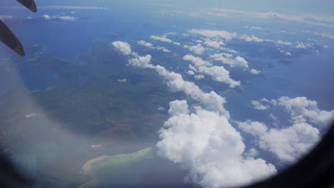 Hand-opens-the-airplane-window-revealing-terrain,-sea-and-clouds