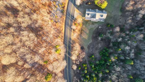 A-drone-shot-of-a-road-cutting-through-the-woods-during-the-fall-and-winter-times-in-New-England