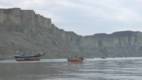 Fischerboote,-Die-Vor-Der-Küste-Von-Gwadar-In-Belutschistan-Festgemacht-Sind,-Mit-Vögeln,-Die-über-Ihnen-Fliegen,-Und-Klippen-Im-Hintergrund