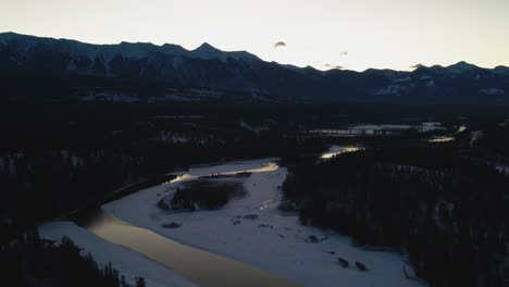 Winter-Landscape-at-Golden-Hour:-Aerial-Panning-Right-Shot-of-Glowing-River-and-Grand-Mountains-in-British-Columbia,-Canada