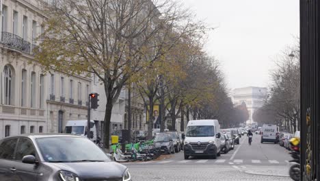 People-and-vehicles-during-rush-hour-in-Paris-8th-arrondisement-with-monumental-Arc-de-Triomphe-in-background