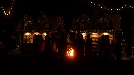 People-gather-around-a-firepit-at-a-Christmas-holiday-festival-at-nighttime