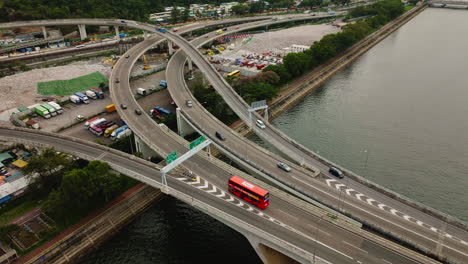 Drone-orbit-shot-of-cars-driving-on-highway-over-waterway-bridge,-Hongkong