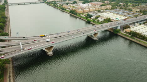 Drone-pan-shot-of-cars-driving-on-highway-over-a-wide-waterway-bridge,-HongKong