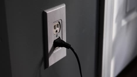 Man-removing-two-plugs-from-an-at-home-electrical-outlet-USA-then-opening-and-closing-a-closet-door