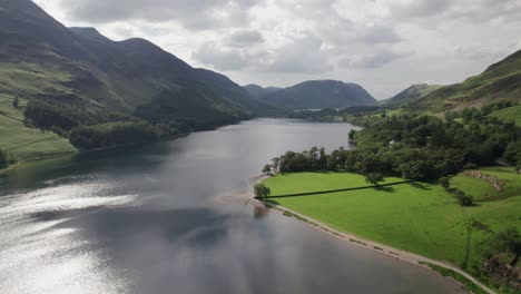 High-drone-shot-flying-backward-over-Crummock-Water-on-a-sunny-day,-Lake-District,-Cumbria,-UK
