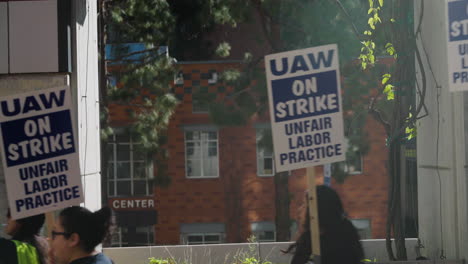 A-Cinematic-Shot-of-UAW-On-Strike-Signs-Passing-by-at-UCLA-for-the-UC-Academic-Workers-Strike