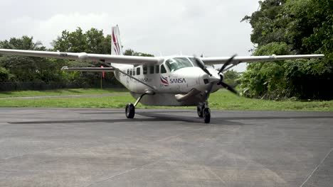 Cessna-208B-Grand-Caravan-EX-from-Sansa-Airlines-taxing-and-parking-after-landing-at-runway,-Follow-shot