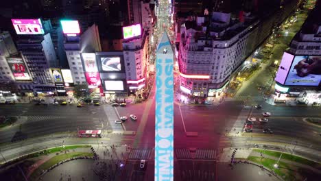 Obelisk-Von-Buenos-Aires-Argentinien-Aus-Der-Luft-Bei-Nacht,-Straßenbeleuchtung-Der-Stadt-In-Der-Innenstadt-Des-Lateinamerikanischen-Pulsierenden-Reiseziels