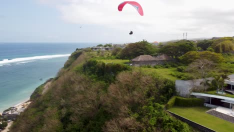 Antena:-Toma-De-Un-Dron-Siguiendo-Un-Parapente-Sobre-Una-Hermosa-Playa-De-Bali