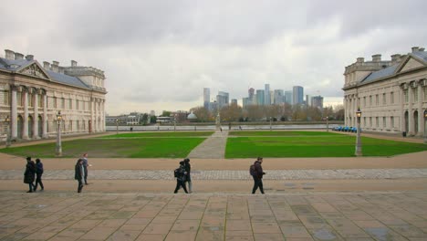 Students-Walking-In-The-Old-Royal-Naval-College-With-London-Skyline-In-The-Background-In-England,-UK