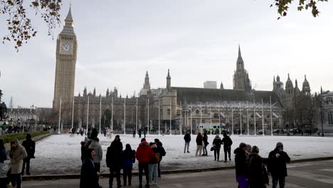 Tourists-At-Snow-Covered-Parliament-Square-Gardens-On-Cold-Winter-Day-In-December-With-Big-Ben-And-Houses-Of-Parliament-In-The-Background