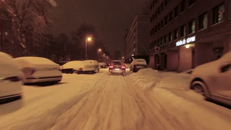 POV-following-shot-of-a-car-driving-carefully-in-deep-snow-past-parked-cars-in-Helsinki