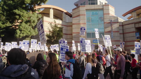 A-Large-Crowd-of-Academic-Workers-on-Strike-March-on-UCLA's-Campus-with-Football-Sign-in-the-Background