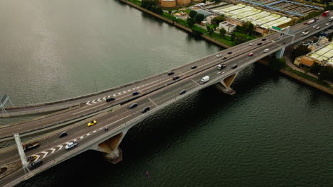 Drone-shot-of-traffic-cars-driving-on-highway-over-a-wide-waterway-bridge,-China