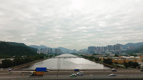 Drone-tilt-shot-of-cars-driving-on-highway-over-a-wide-waterway-bridge,-HongKong
