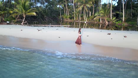 Young-pretty-woman-walking-back-and-forth-with-long-skirt-on-beach
