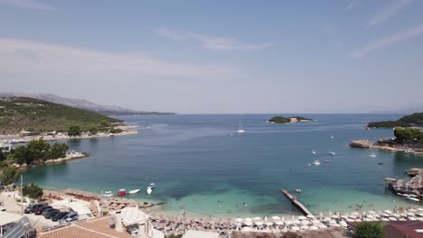 Aerial-over-idyllic-tourist-beach-and-bay-in-Ksamil---summer-day,-people-swim