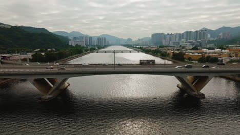Drohnenaufnahme-Von-Autos,-Die-Auf-Der-Autobahn-über-Eine-Breite-Wasserstraßenbrücke-In-Hongkong-Fahren