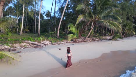 Woman-walking-with-long-skirt-through-waves-on-natural-paradise-beach