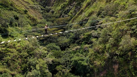 Brave-person-with-helmet-walking-and-crossing-Tibetan-rope-bridge-over-Peruvian-Amazonian-valley