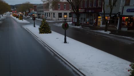 Beautiful-low-cinematic-aerial-shot-of-lit-Christmas-trees-lining-main-street-in-Wellsboro-PA