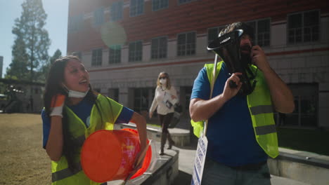 A-Man-and-Woman-Strike-Leader-Bang-a-Drum-and-Chant-into-a-Megaphone-on-Campus-at-UCLA's-Academic-Workers-Strike