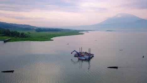 Digger-boat-on-the-lake-with-mountains-in-the-background,-Ambarawa,-Indonesia